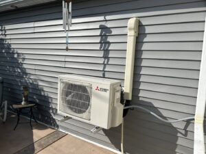 A Mitsubishi Electric outdoor mini-split condenser unit installed on a house wall by Climate Diagnostics in Buffalo, NY.