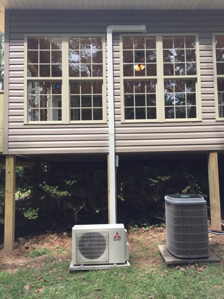 An outdoor Mitsubishi mini-split unit and a traditional AC condenser unit installed at a residential property by Douglas Cooling & Heating in Pelham, AL.