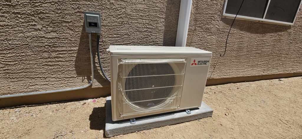 A Mitsubishi Electric mini-split outdoor condenser unit installed against a residential wall by HoxAir Heating & Cooling in Phoenix, AZ