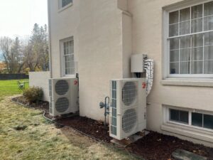 Two Mitsubishi mini-split outdoor condenser units installed on the side of a building by Semenik Hvac/r in Spokane, WA.