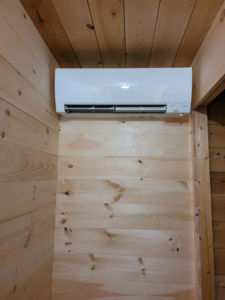 An indoor Mitsubishi mini-split head unit professionally installed on a wooden wall by Maine Thermal Energy Services in Ellsworth, ME