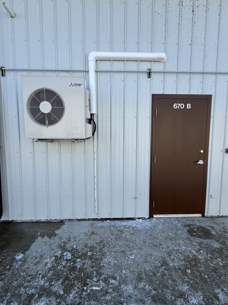 A Mitsubishi mini-split outdoor unit installed on the side of a commercial building by Elite Home Comfort in Clarksville, TN