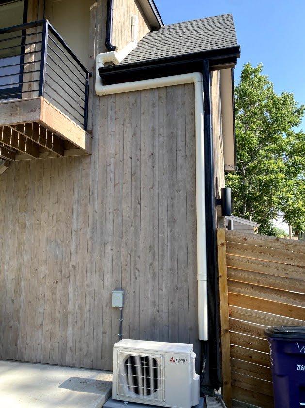 A Mitsubishi mini-split outdoor unit installed on the side of a building by Husky Heating and Cooling in Westminster, CO.