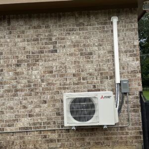 A Mitsubishi Electric mini-split outdoor unit installed on a brick wall by EZ Comfort Air Conditioning & Heating LLC in Humble, TX.