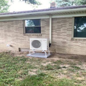 A Mitsubishi mini-split outdoor condenser unit installed next to a residential building by Terry Allen Plumbing & Heating in Flint, MI.