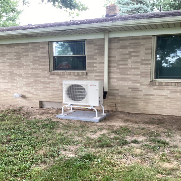 A Mitsubishi mini-split outdoor condenser unit installed next to a residential building by Terry Allen Plumbing & Heating in Flint, MI.