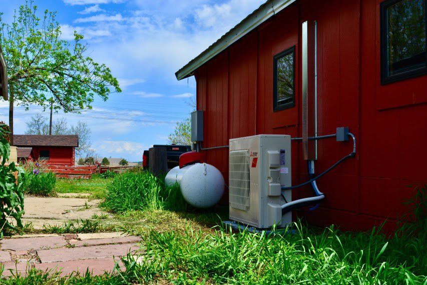 A Mitsubishi mini-split outdoor unit installed next to a propane tank by Husky Heating and Cooling in Westminster, CO.