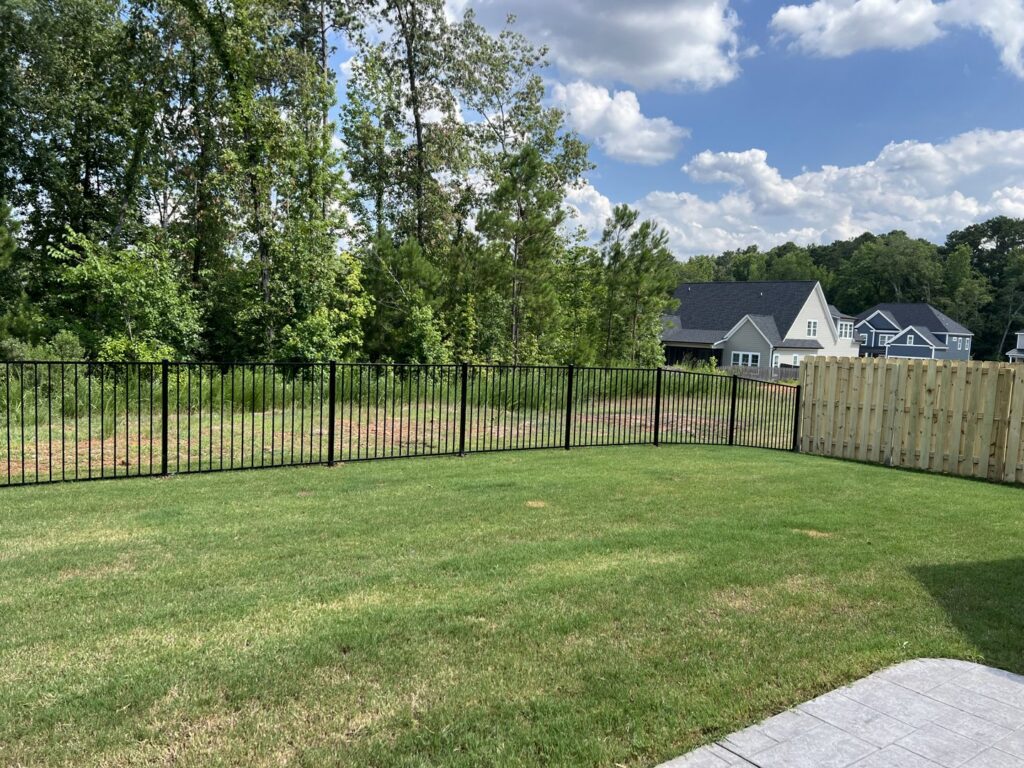 A backyard featuring a combination of black ornamental metal and wood privacy fence installed by East Georgia Fence in Evans, GA.