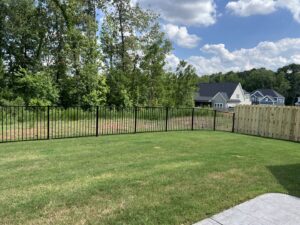 A backyard featuring a combination of black ornamental metal and wood privacy fence installed by East Georgia Fence in Evans, GA.