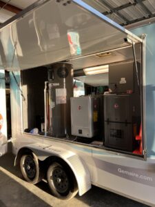 A mobile showroom trailer displaying various HVAC equipment like water heaters and furnaces from Green Dot Heating & Air in Wilmington, NC.