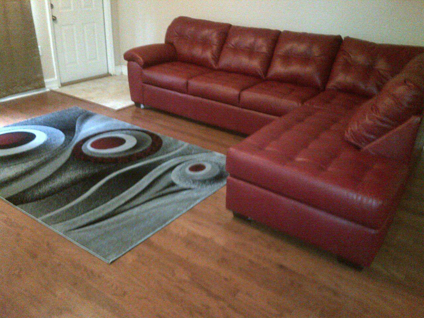 A modern patterned area rug complementing a red sectional sofa on a hardwood floor by Sunshine Rugs and Art in Londonderry, NH.
