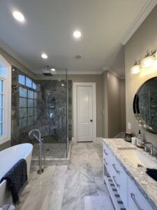 A modern bathroom featuring newly installed recessed ceiling lights and vanity lighting by Copper And Current Electrical Services in Greensboro, NC.