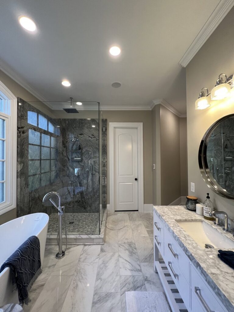A modern bathroom featuring newly installed recessed ceiling lights and vanity lighting by Copper And Current Electrical Services in Greensboro, NC.