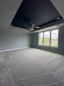 Modern bedroom with new gray carpet installation and a dark accent ceiling by Castro's Carpet in Houston, TX.
