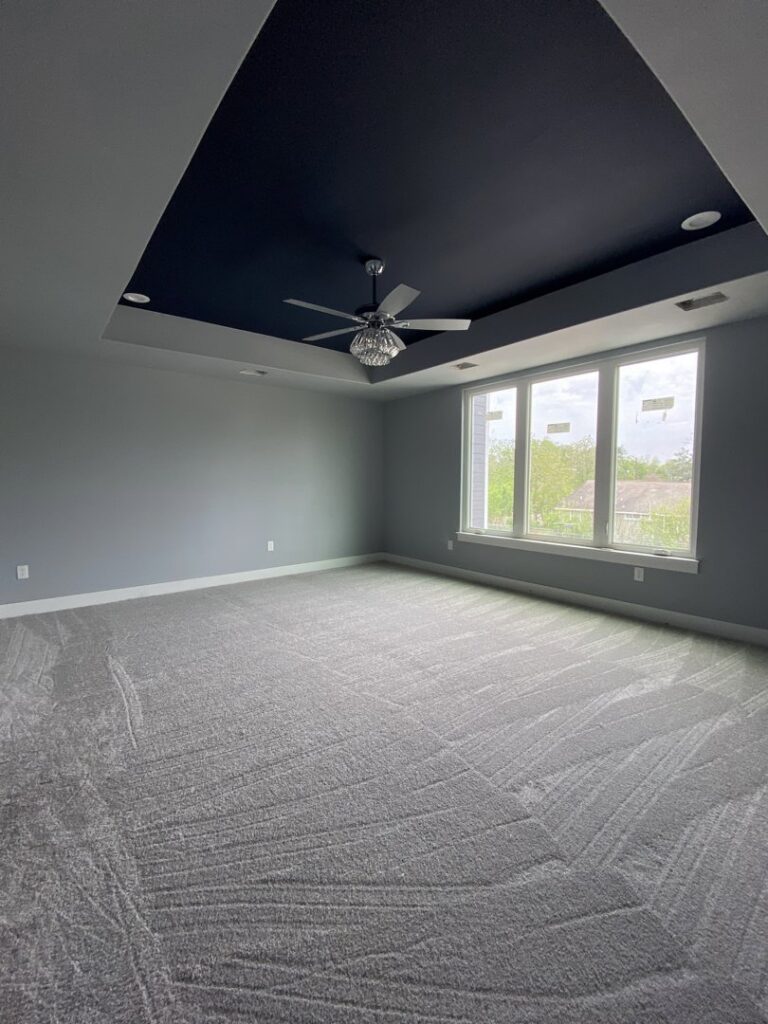 Modern bedroom with new gray carpet installation and a dark accent ceiling by Castro's Carpet in Houston, TX.