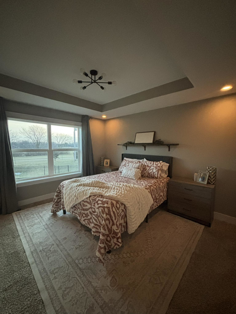 A modern bedroom featuring a newly installed ceiling light fixture and recessed lighting by Woodford Power & Light Co. in Ankeny, IA.