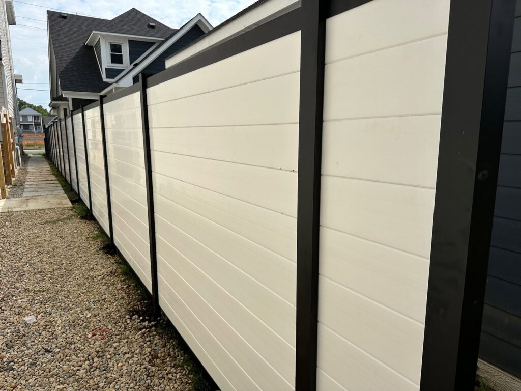 A modern black and white horizontal privacy fence installed along a narrow pathway by Render Fences in Fishers, IN.