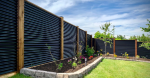 A modern black corrugated metal fence with wooden posts installed by Fortaleza Concepts in Clovis, NM.