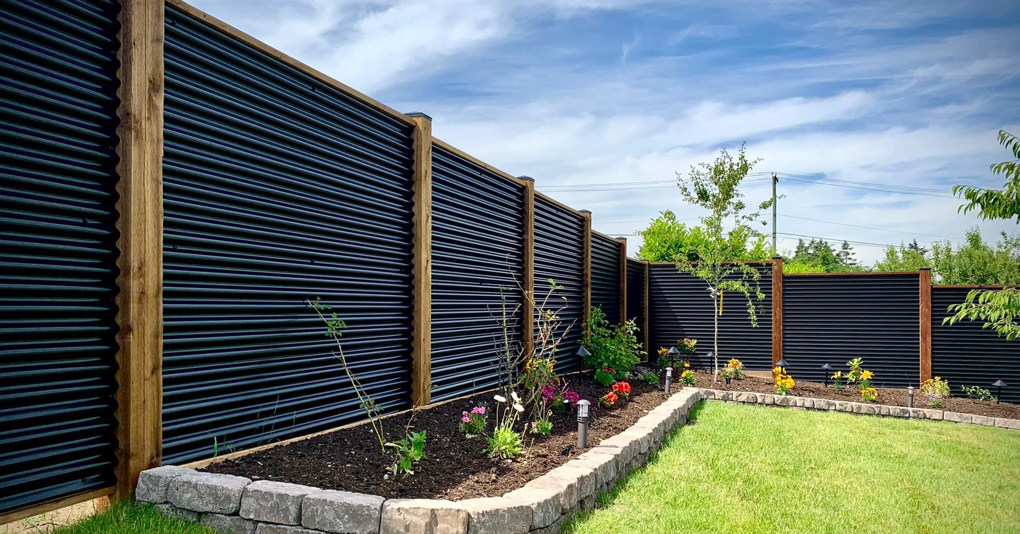 A modern black corrugated metal fence with wooden posts installed by Fortaleza Concepts in Clovis, NM.