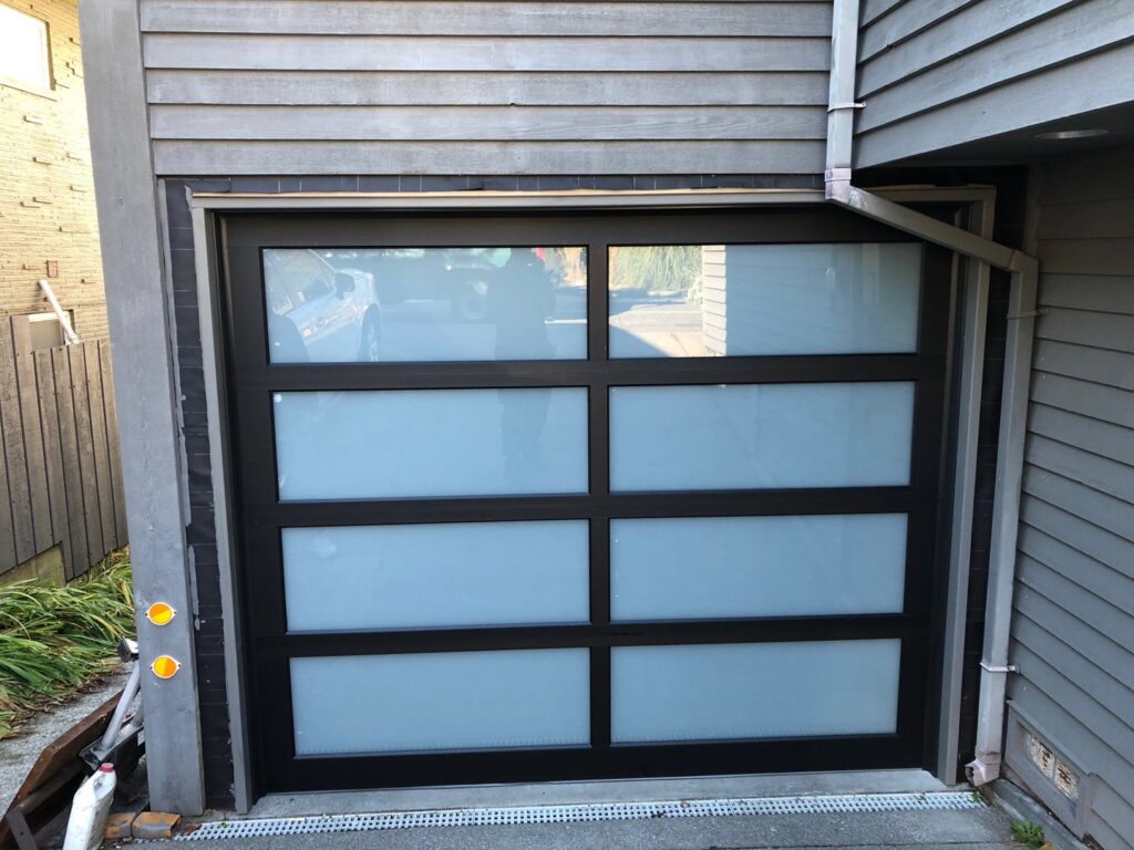 A modern black garage door with frosted glass panels installed by Steadfast Garage Door Services LLC in Federal Way, WA.