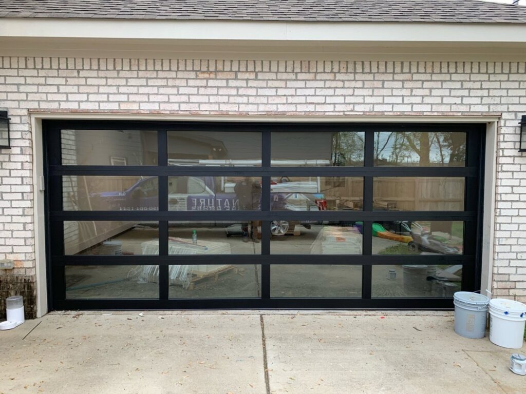 A sleek modern black full-view glass garage door installed by Signature Garage Doors in Huntsville, AL.