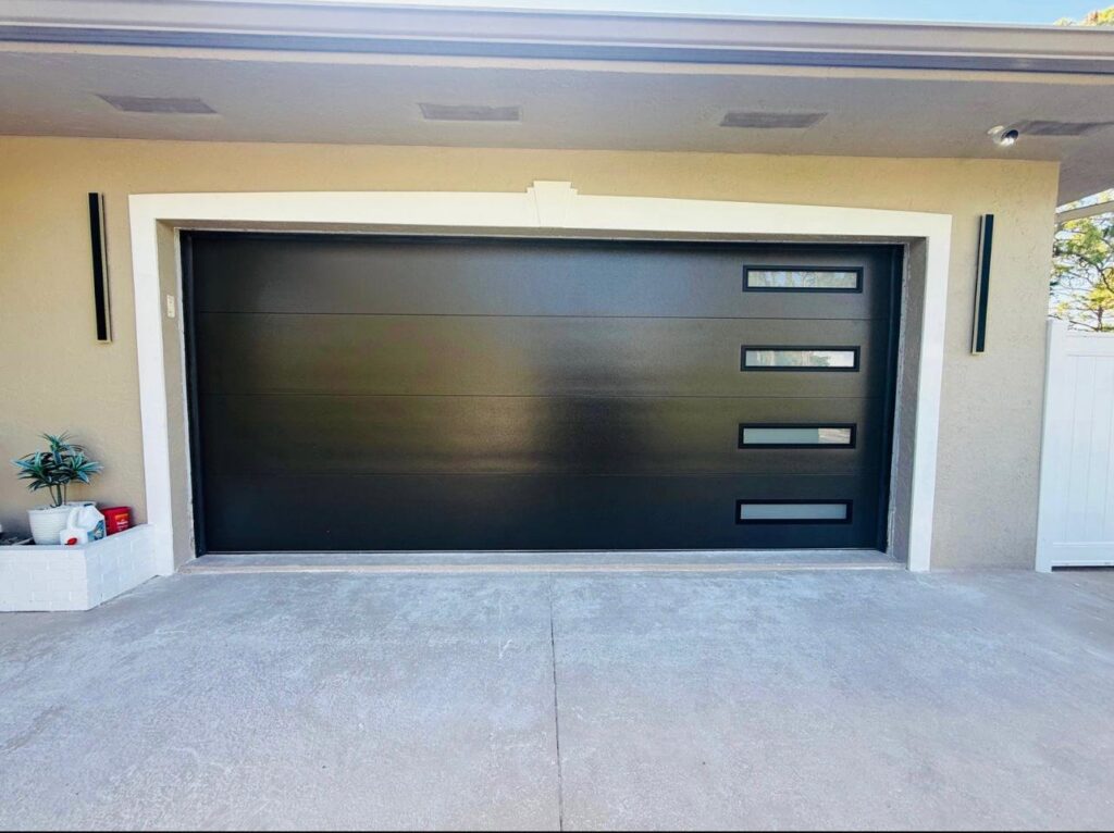 A newly installed modern black garage door with horizontal windows on a house, completed by BSD Garage Door Service in Naperville, IL.