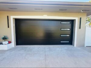 A newly installed modern black garage door with horizontal windows on a house, completed by BSD Garage Door Service in Naperville, IL.