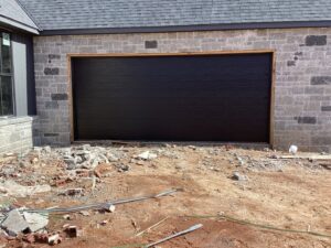 A modern black garage door installed in a new construction home by CCM Overhead Doors in Oklahoma City, OK.