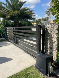 A modern black horizontal-slat sliding gate with a gate operator motor installed by Motor & Fence Solutions in Miami, FL.