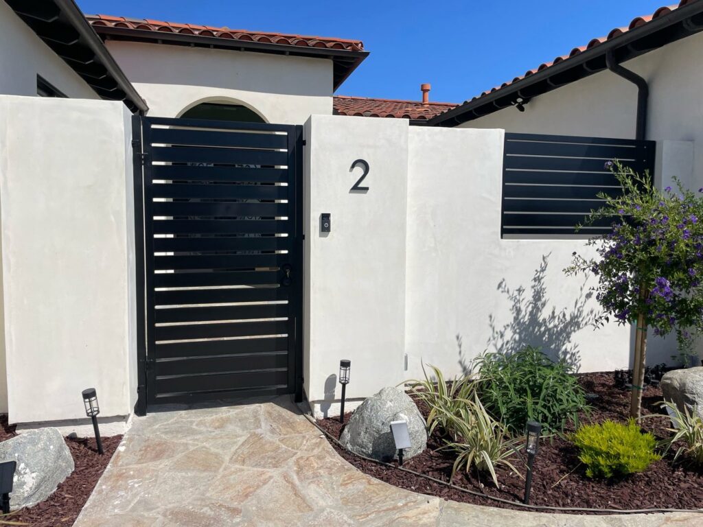 A modern black horizontal slat pedestrian gate and matching fence panel installed by Coastline Gate Repair in Los Angeles, CA.