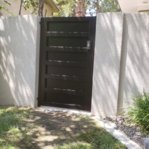 A modern black metal gate with horizontal panels and a keypad installed by Custom Customs Inc. in Henderson, NV