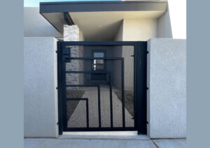 A modern black metal pedestrian gate with a geometric design, installed by City Iron LLC in Albuquerque, NM.