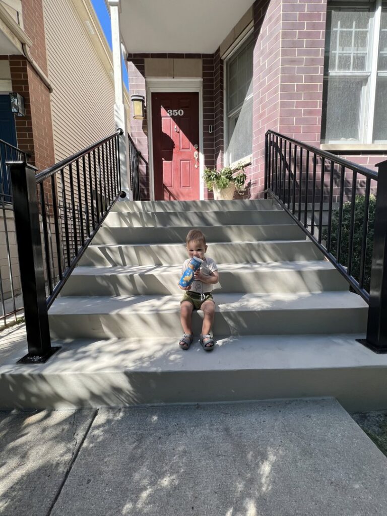 Modern black metal stair railings installed on outdoor concrete steps by Ironcraft Welding in Chicago, IL.
