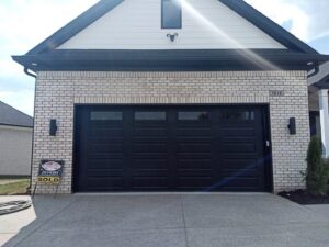A modern black residential garage door installed on a new home by Honest Overhead Garage Doors in Elizabethtown, KY.