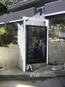 A modern black horizontal slat gate with white support posts installed by Los Angeles Fence Builders in Los Angeles, CA.