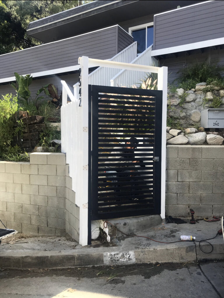 A modern black horizontal slat gate with white support posts installed by Los Angeles Fence Builders in Los Angeles, CA.