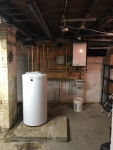 A modern wall-mounted boiler and a white hot water heater tank installation by Nate's Oil Burner Service in New Bedford, MA