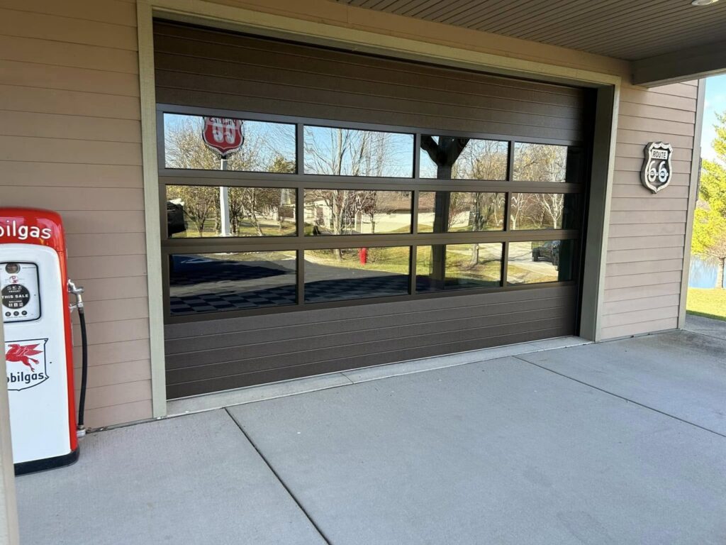 A modern brown garage door with multiple glass panels, showcasing a stylish installation by Overhead Doors Unlimited, LLC in Appleton, WI.