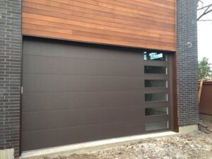 A modern brown garage door with horizontal windows installed on a brick house by Sonoran Garage Doors in Mesa, AZ
