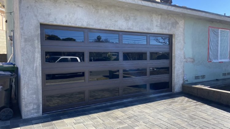 A modern brown garage door with multiple glass panels installed by Anew Garage by Jon's Garages in Surprise, AZ.