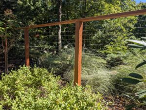 A modern cable railing fence with wooden posts in a garden by RP Fencing & Gates in Brewster, NY