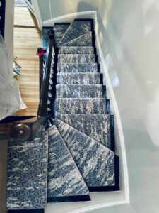 A modern patterned carpet runner installed on a winding staircase by Harry's Carpet One in Quincy, MA.