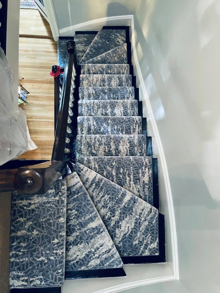 A modern patterned carpet runner installed on a winding staircase by Harry's Carpet One in Quincy, MA.