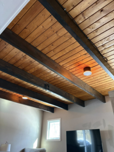 Modern ceiling light fixtures expertly installed on a wooden beamed ceiling by East West Electric LLC in Chester, NH.
