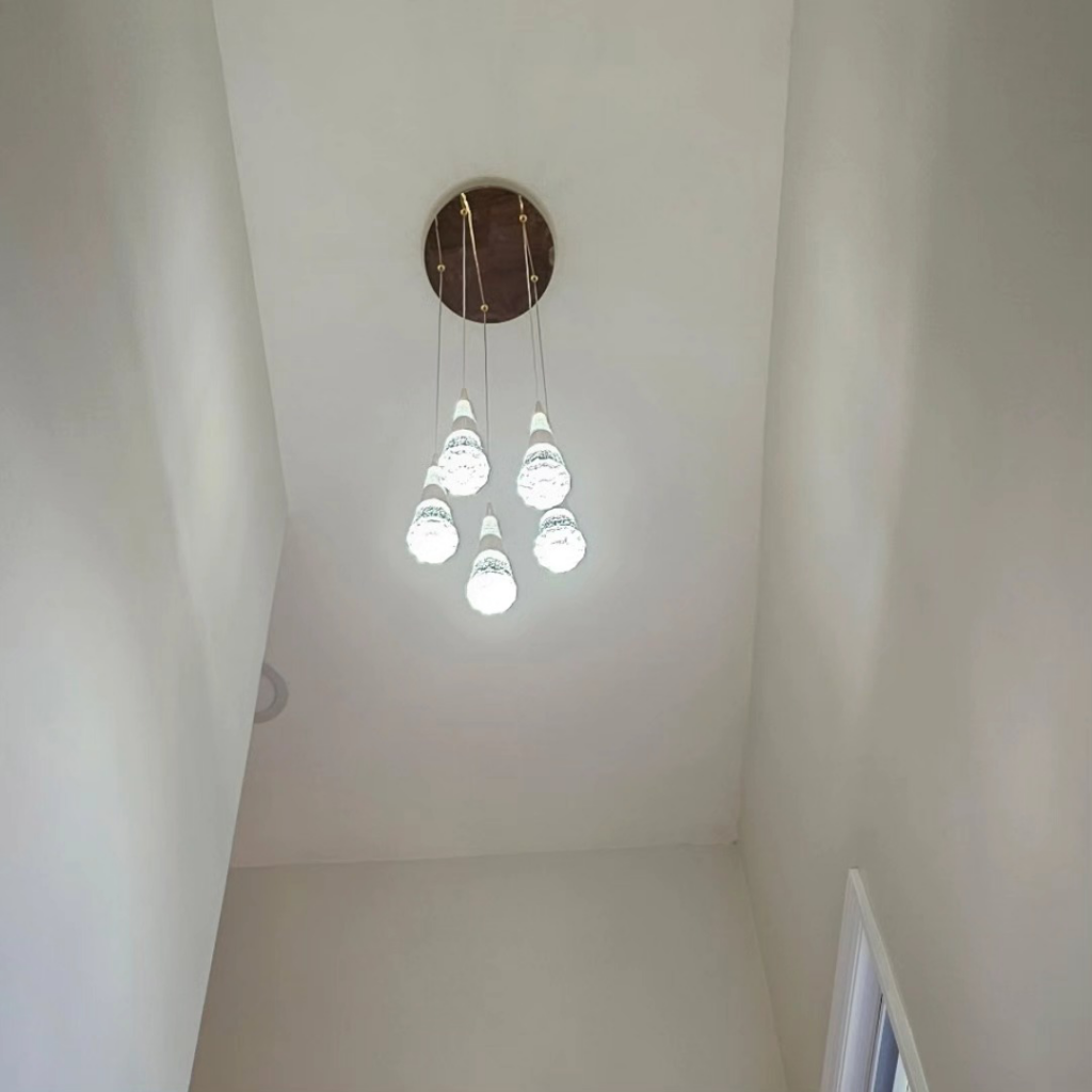 A modern chandelier with multiple lights installed in a high ceiling by C&J And Sons Multi Services in Newark, NJ.