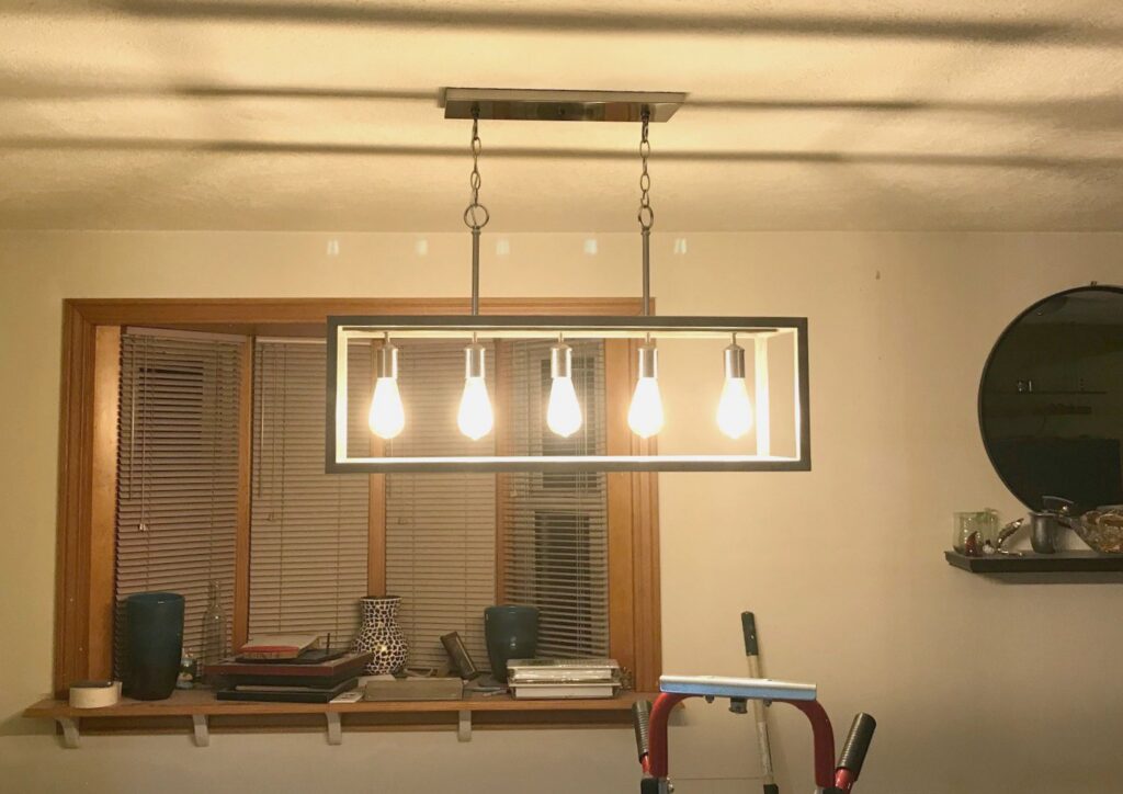 A modern rectangular chandelier installation in a home by Olectric in Reno, NV.