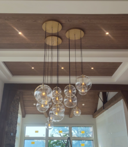 A modern multi-globe chandelier and recessed lighting installed in a wooden ceiling by Ryco Electric in York, PA
