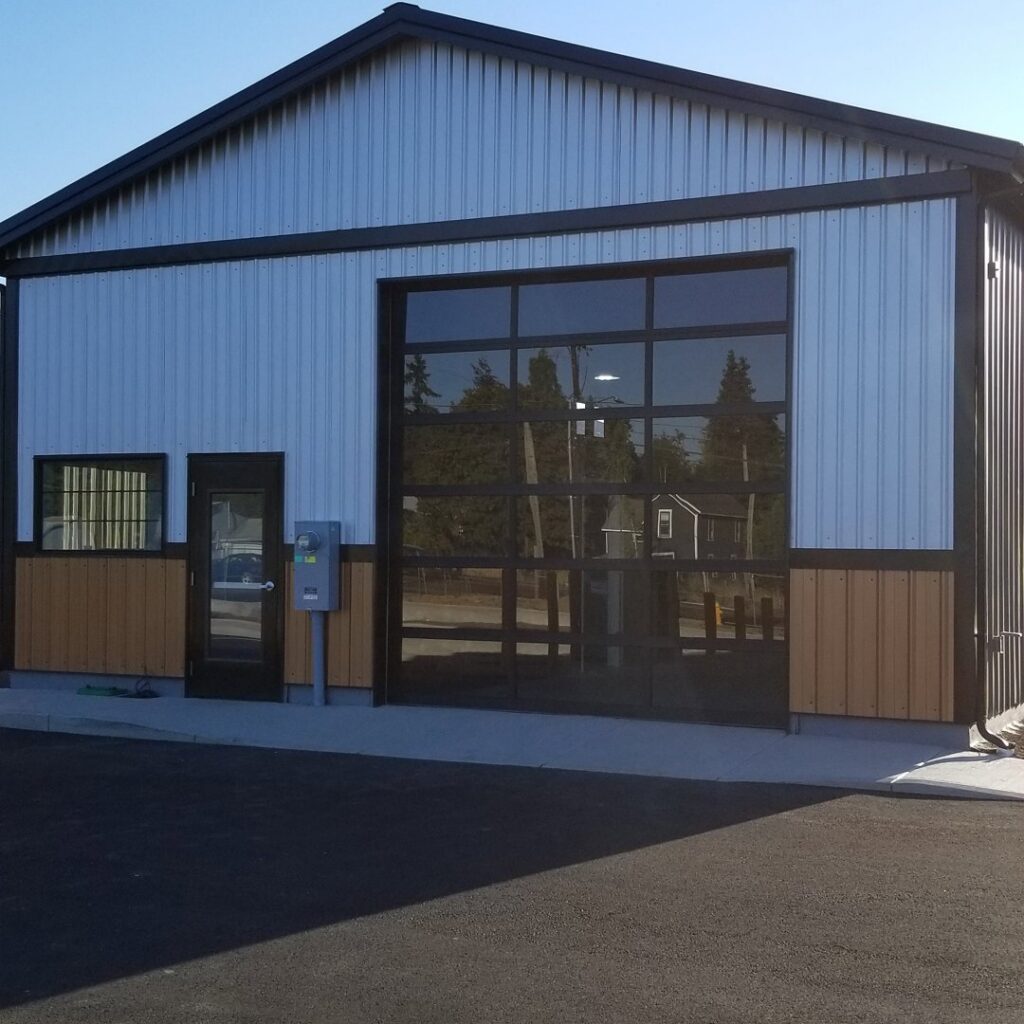 A modern commercial building featuring a large glass garage door installed by Xpress Doors LLC in Salem, OR