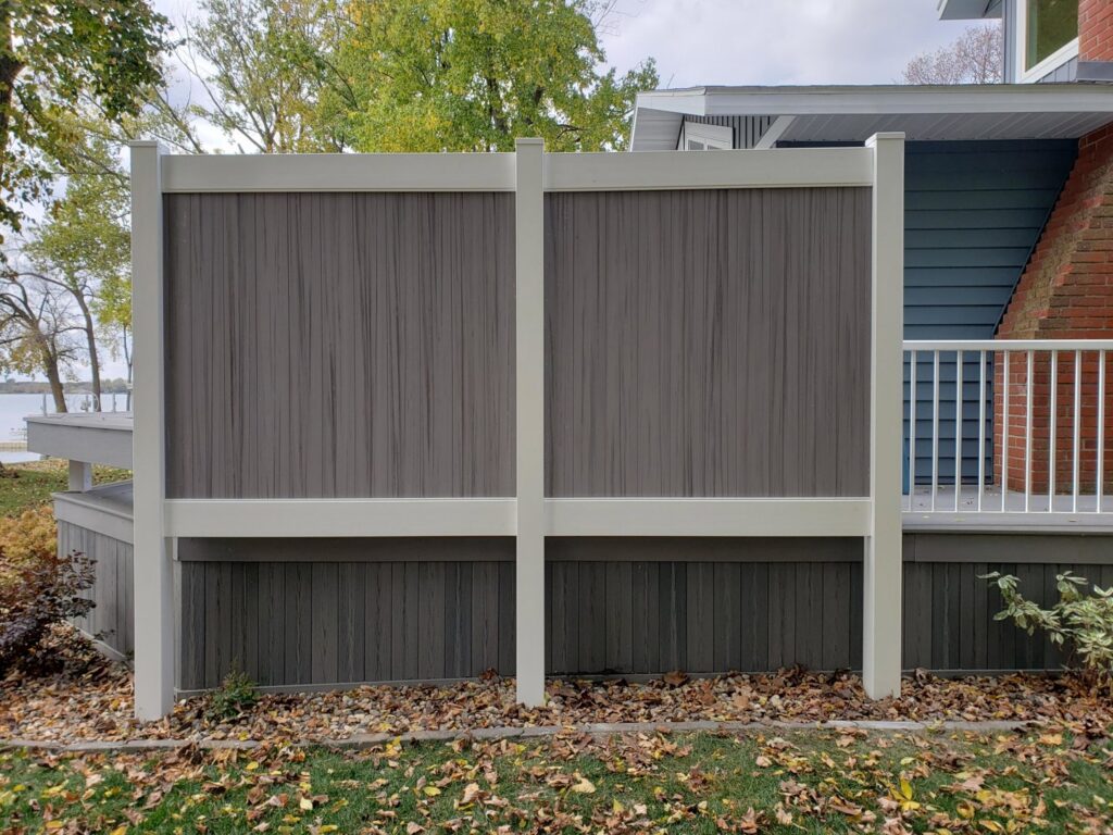 Modern composite privacy fence with grey panels and white posts installed by a lake by Wildfire Products Inc. in West Fargo, ND