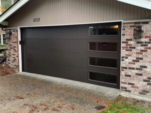 A newly installed modern dark brown garage door with horizontal windows by Overhead Door Company of Everett, Inc in Everett, WA.